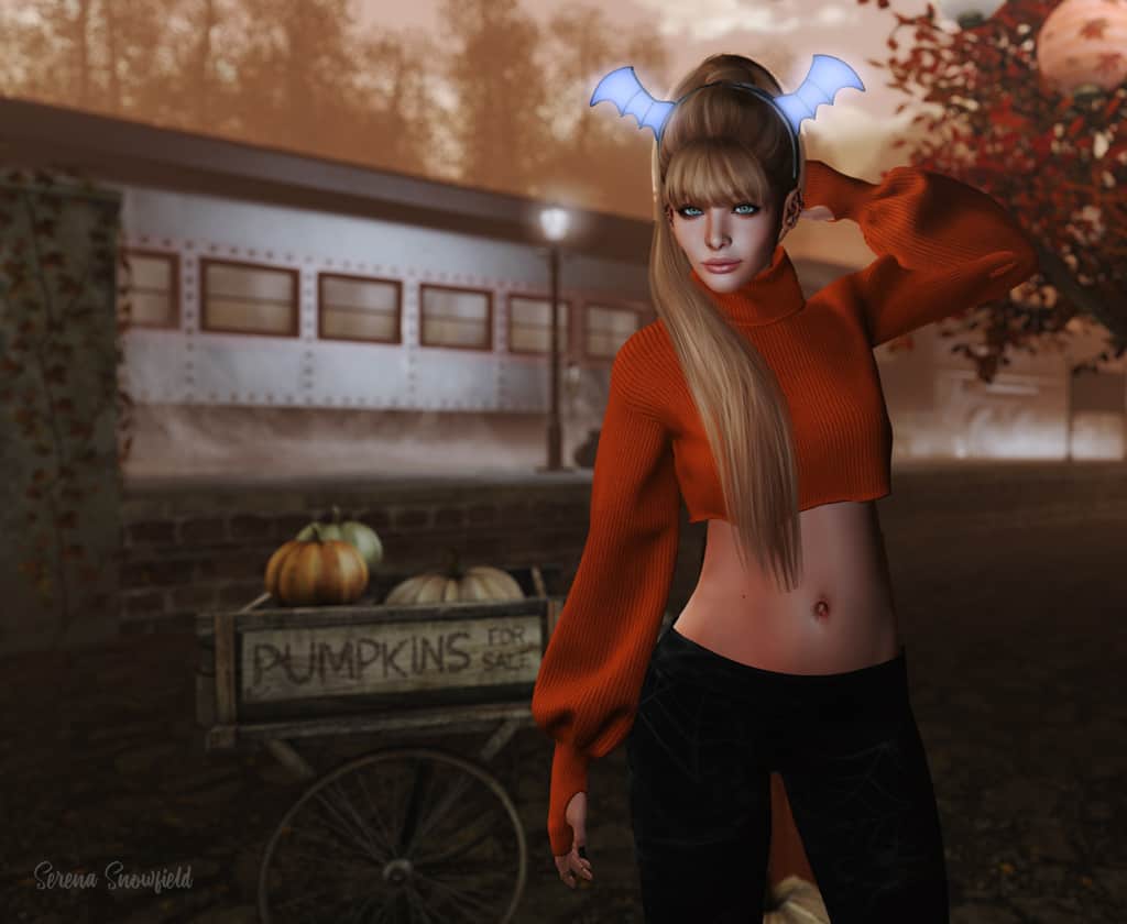 Girl in an orange turtleneck sweater with a glowing bat wing headband.